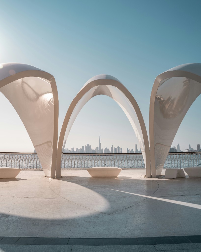 Dubai skyline seen through white waterfront arches